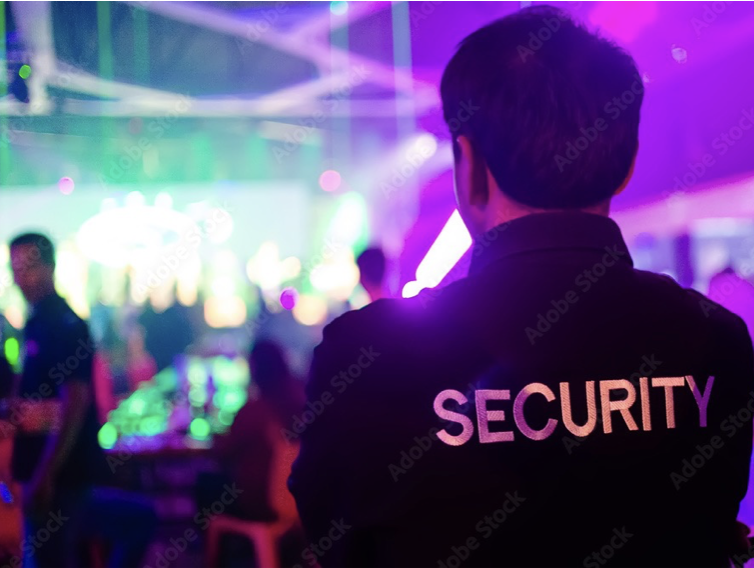 A man in black jacket with security on back.