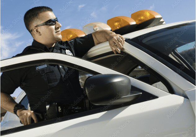 A police officer sitting in his car with the lights on.