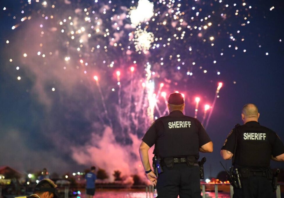 A police officer watching fireworks at night.